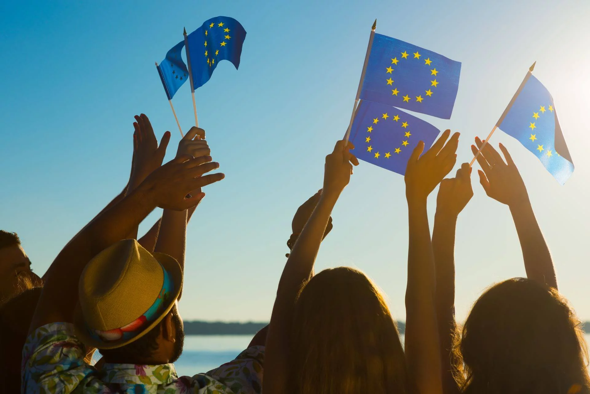 Miksi kannattaa rekisteröidä vaihtoehtoisia verkkotunnuksia? Kuvassa ihmisiä rannalla heiluttamassa EU:n lippuja.